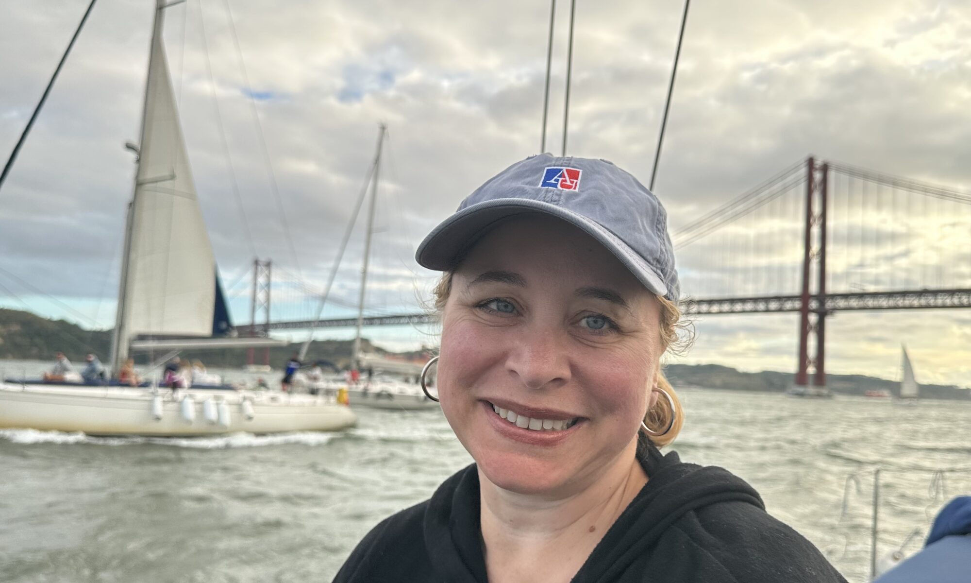 Joyce Warner wearing a baseball cap with a sailboat and a bridge in the background