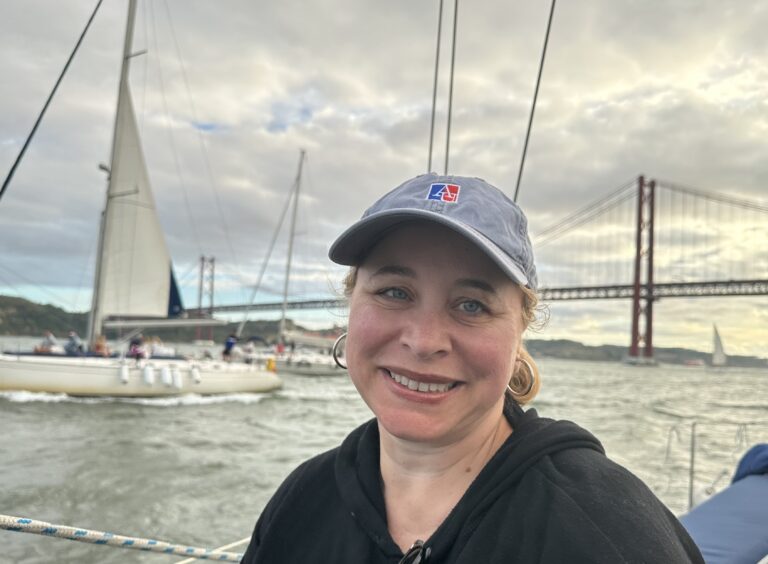 Joyce Warner wearing a baseball cap with a sailboat and a bridge in the background